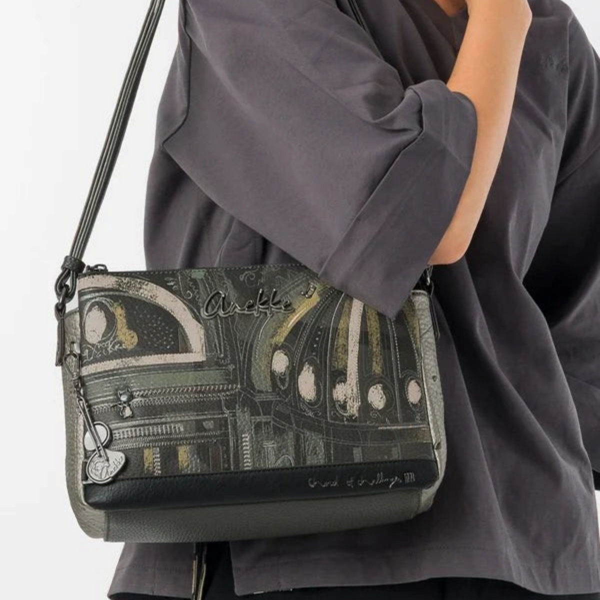 Lieblingstasche cross-body bag featuring a dark metallic architectural print and a decorative charm on the strap.