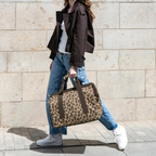 Lieblingstasche Allrounder L travel bag in leopard print with sturdy handles, carried by a woman in casual attire.