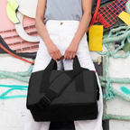 Lieblingstasche Allrounder M black travel bag with padded shoulder strap and metal frame closure held by a person.