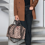 Lieblingstasche Allrounder M travel bag in leopard print with brown straps, held by a woman in a brown blazer.