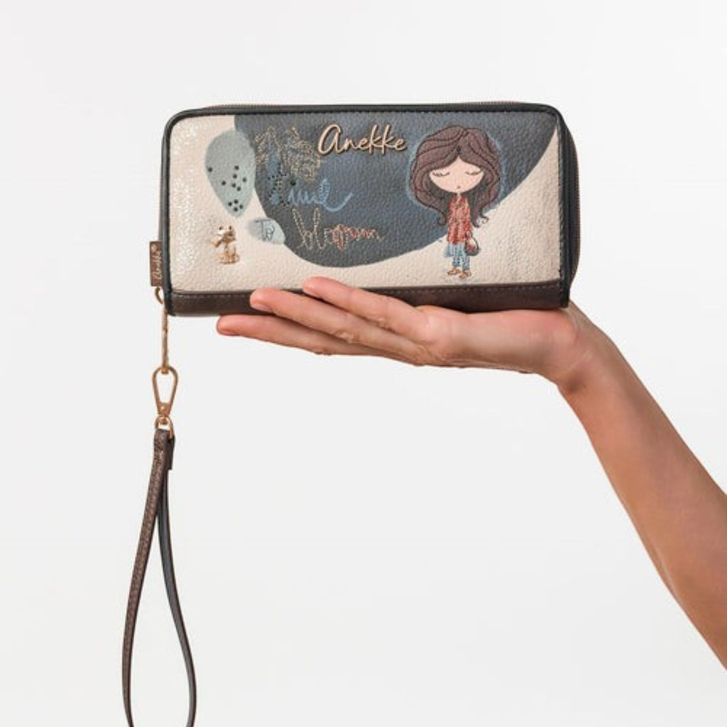 Lieblingstasche Anekke wallet with illustrated girl, floral details, and wrist strap held in a hand