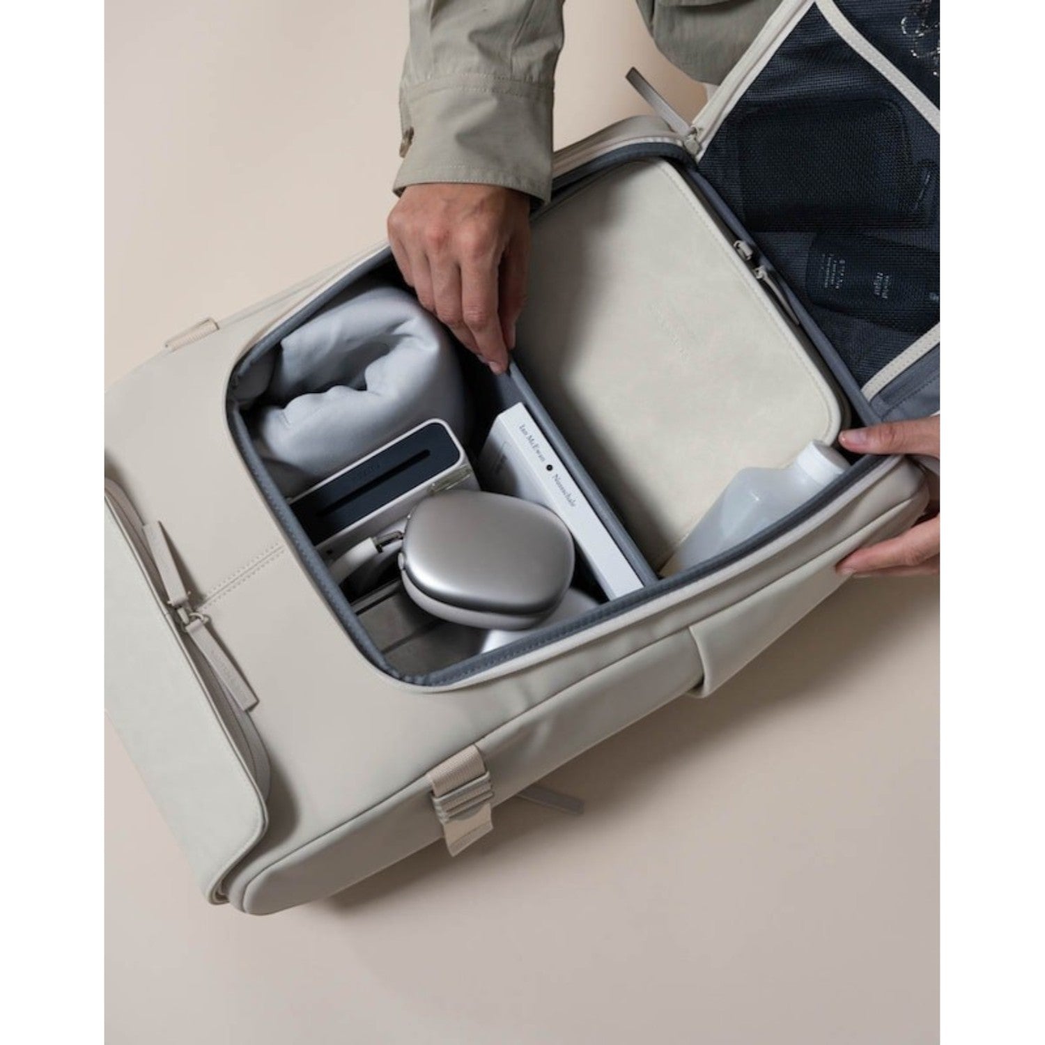 Lieblingstasche Bali Pro beige travel backpack open, showing organized packing with headphones, book, and toiletries.
