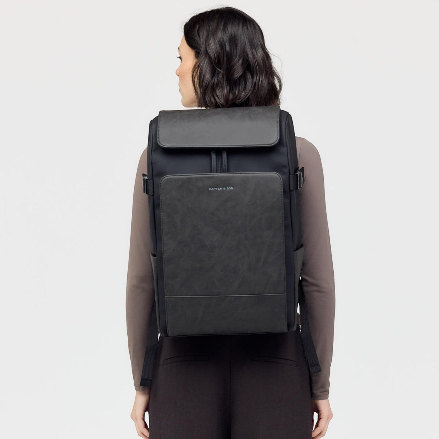 Lieblingstasche Bali Pro black backpack with faux leather front panel and adjustable straps, worn by a woman.