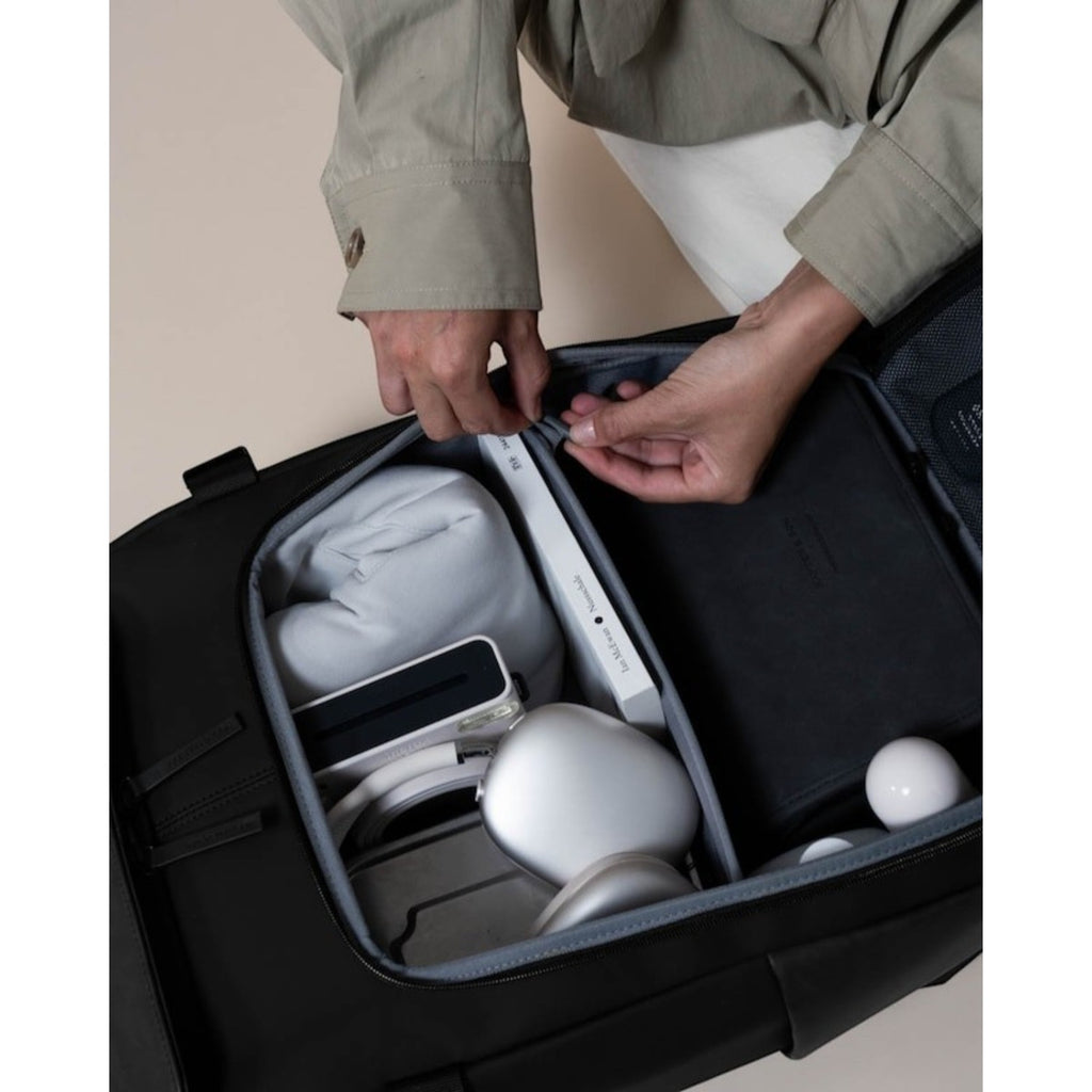 Lieblingstasche Bali Pro black backpack interior with organized tech accessories, headphones, and book.