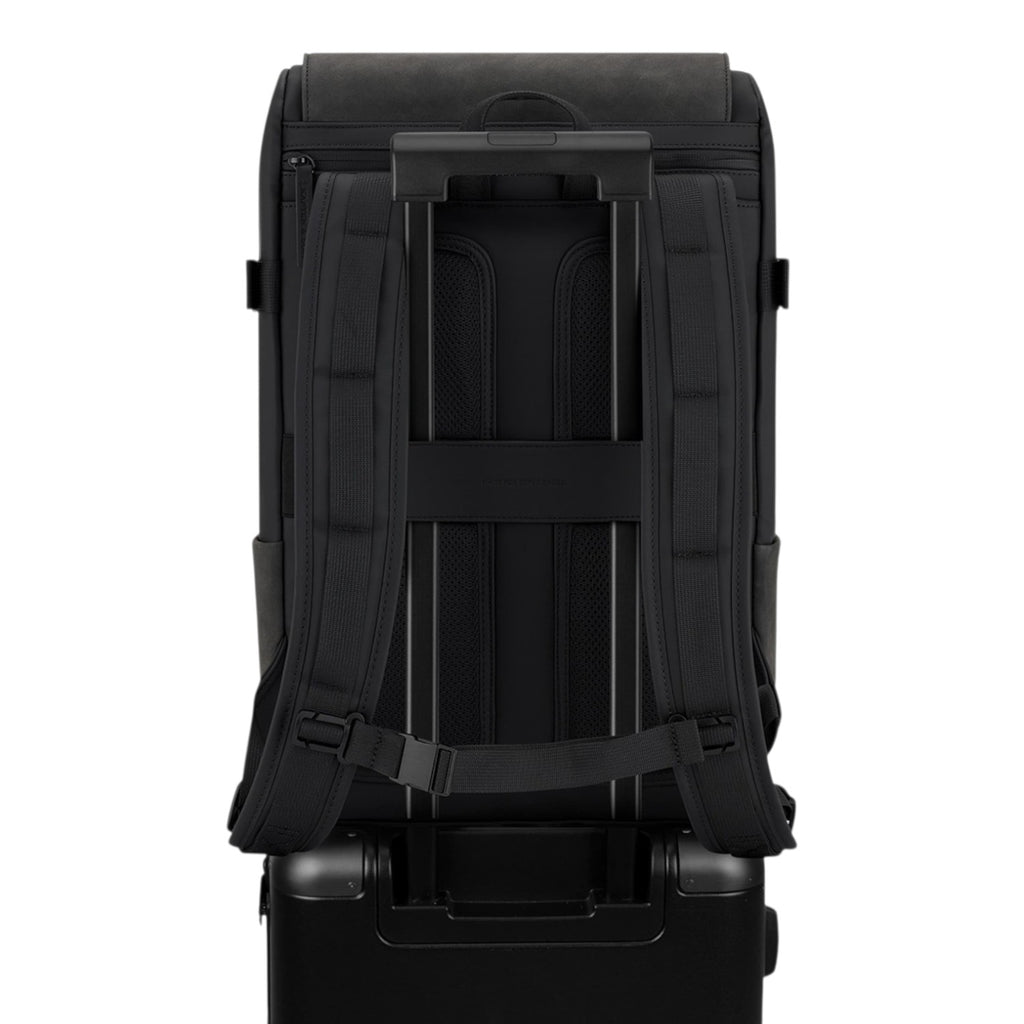 Lieblingstasche Bali Pro black backpack with padded straps and trolley sleeve, attached to a black suitcase.