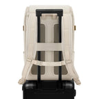 Lieblingstasche Bali Pro cream vegan leather backpack with padded straps and luggage sleeve, attached to a black suitcase.