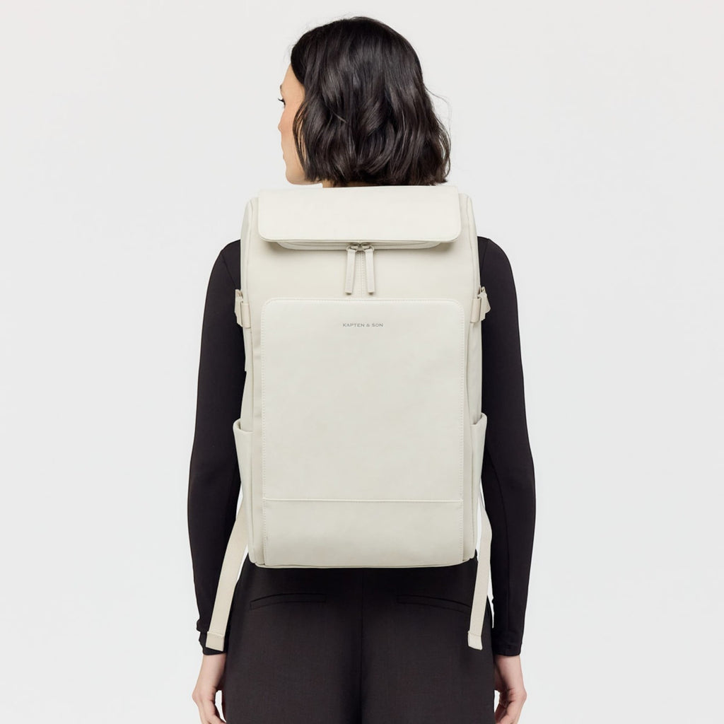 Lieblingstasche Bali Pro light grey vegan leather backpack with multiple pockets and zippers, worn by a woman.