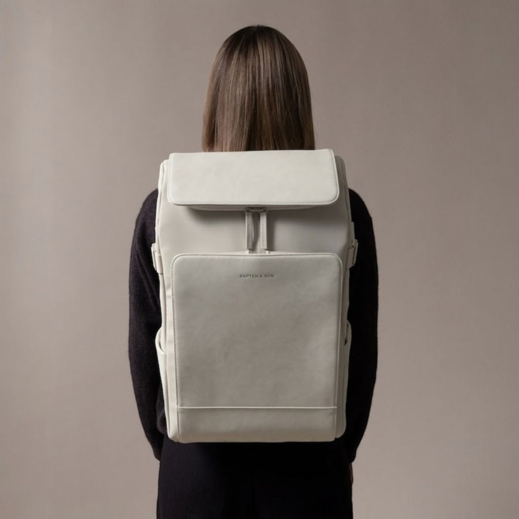 Lieblingstasche Bali Pro light grey vegan leather backpack with flap closure and front pocket, worn by a person.