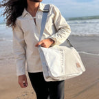 Lieblingstasche Barkasse white sailcloth messenger bag with unique stitching worn by a man on a sunny beach