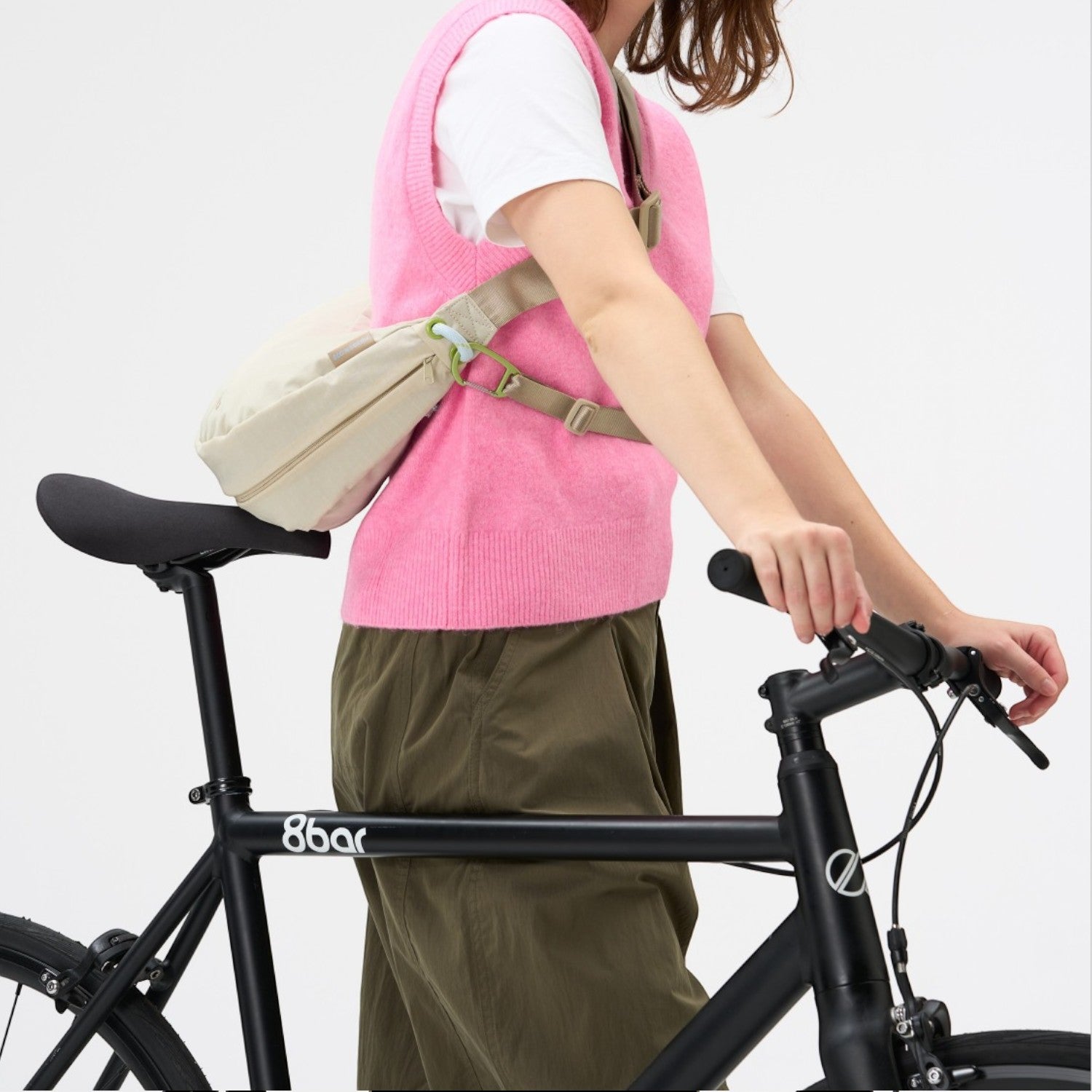 Lieblingstasche beige sling bag worn by a woman in a pink vest riding a black bicycle