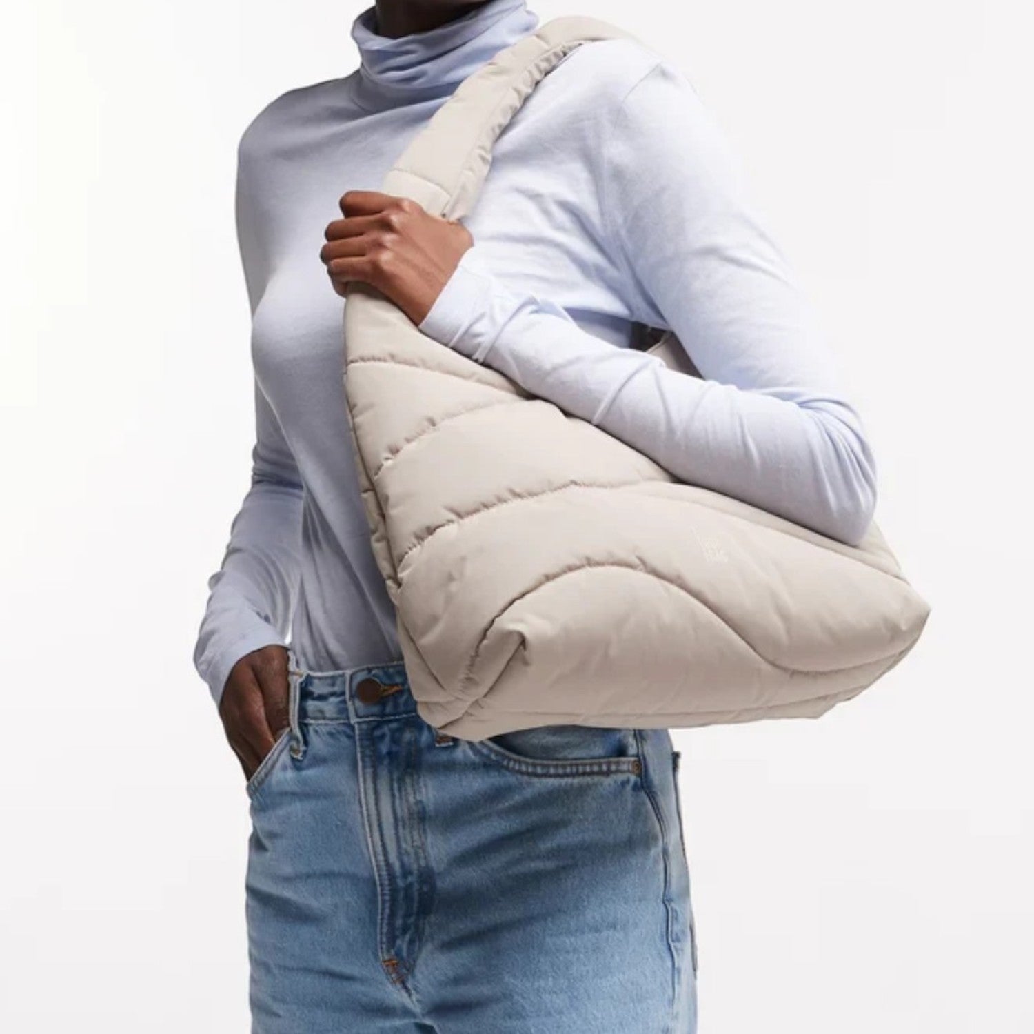 Lieblingstasche beige wavy puffer shoulder bag worn by a smiling woman in a light blue turtleneck