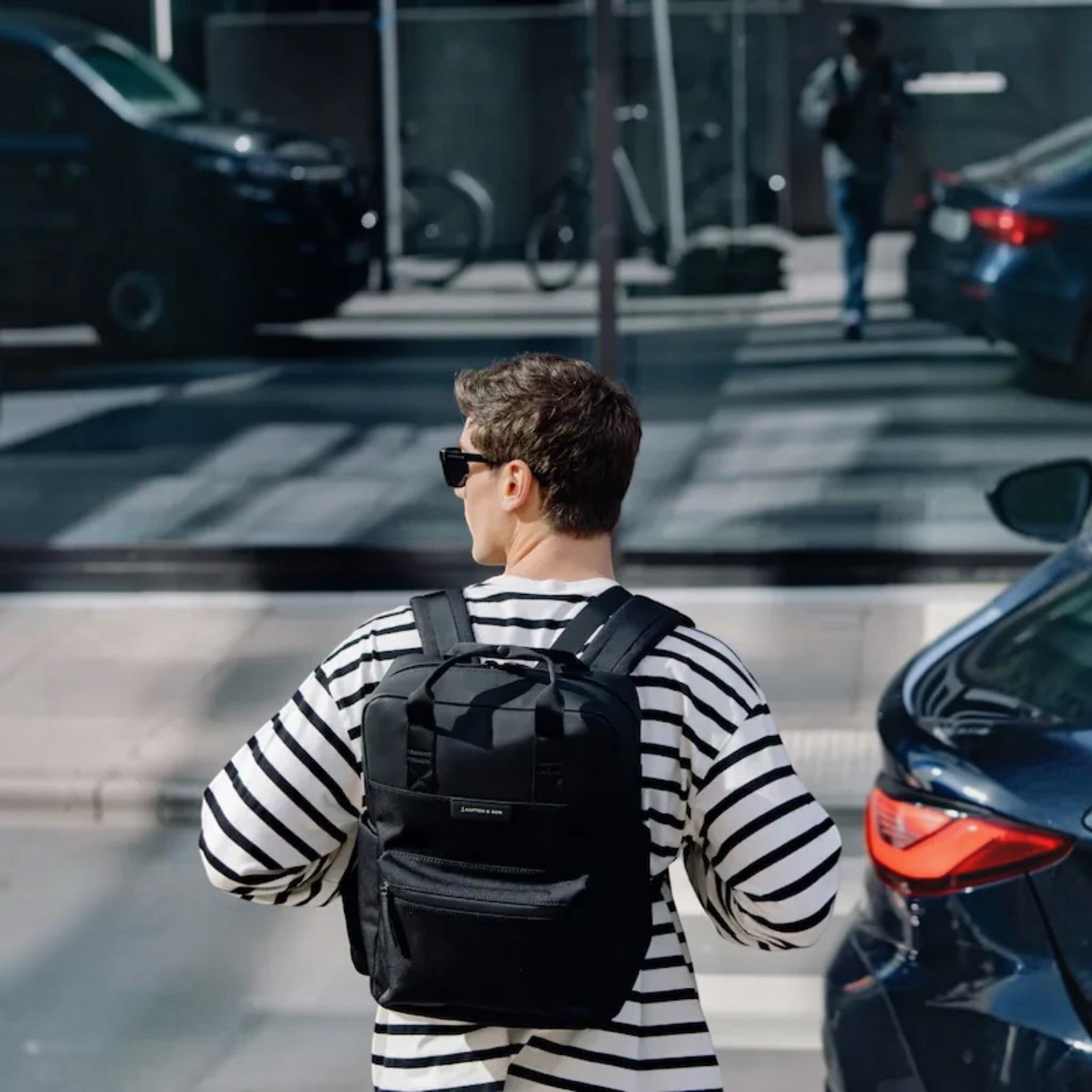 Lieblingstasche Bergen Pro black backpack worn by a man in a striped shirt on a city street