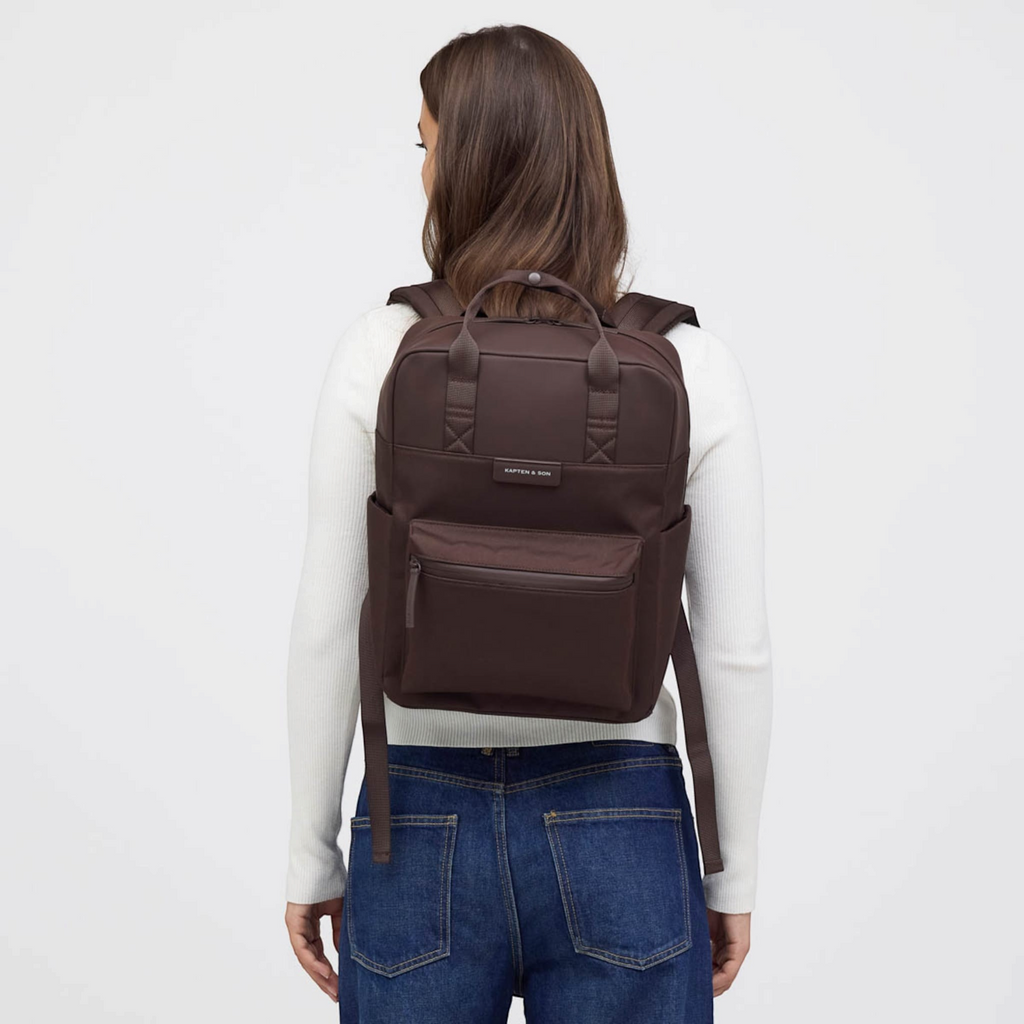 Lieblingstasche Bergen Pro dark brown backpack worn by a woman with a white long-sleeve top and blue jeans