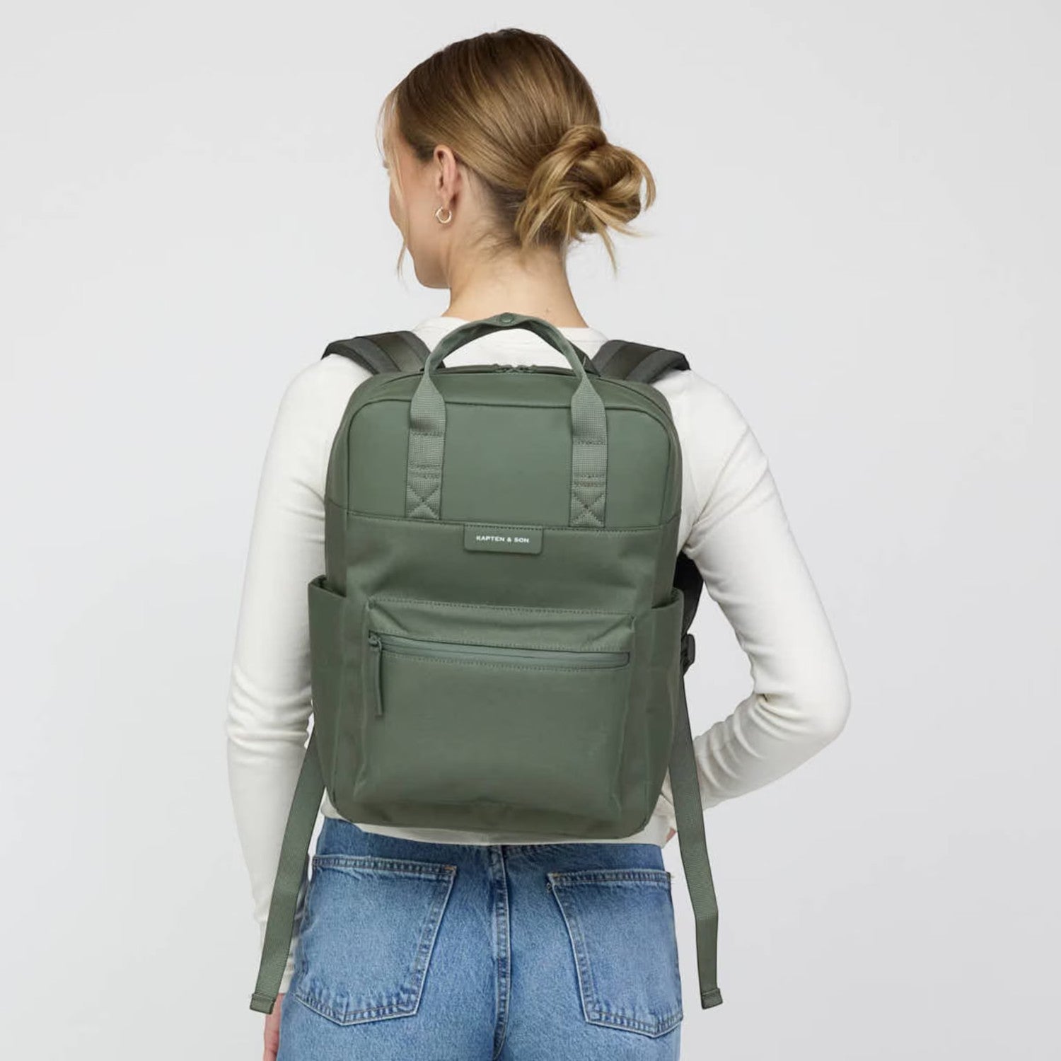 Lieblingstasche Bergen Pro backpack in olive green, worn on the back by a woman in a white long-sleeve shirt.