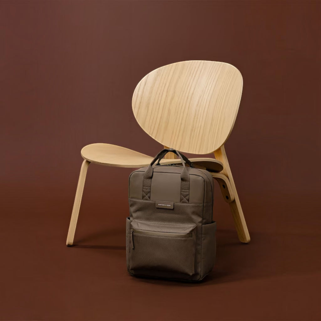Lieblingstasche Bergen Pro backpack in taupe with padded straps and laptop compartment against a wooden chair