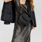 Lieblingstasche Big Sister black leather crossbody bag worn by a woman in a metallic dress and black jacket