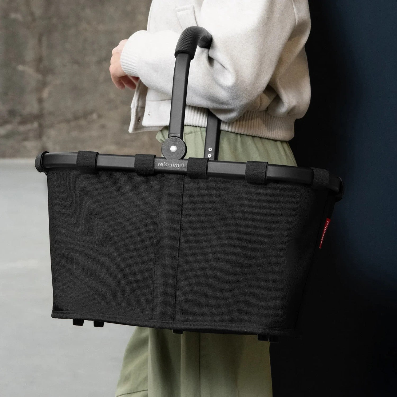 Lieblingstasche black Carrybag shopping basket with a sturdy aluminium handle held by a person in casual clothing