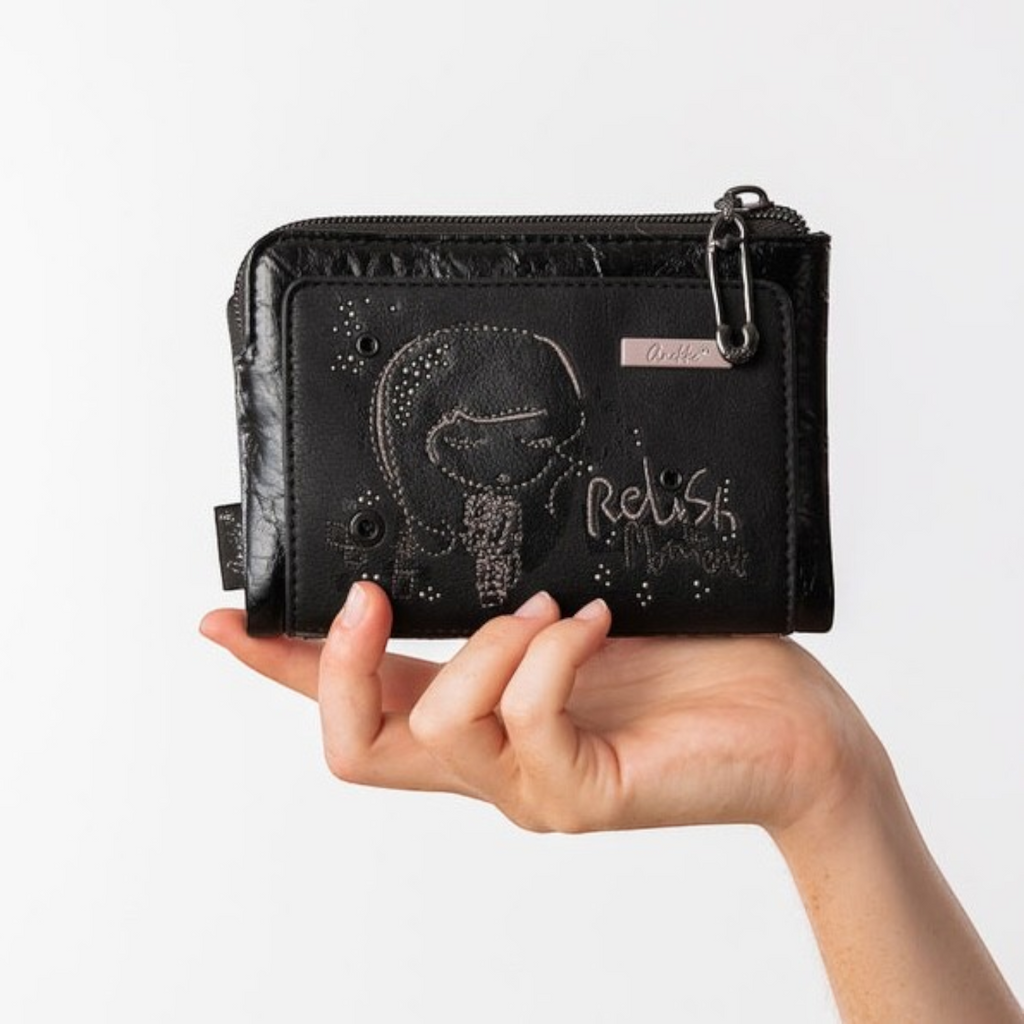 Lieblingstasche black wallet with embossed girl graphic and Relish the Moment text, held in a hand