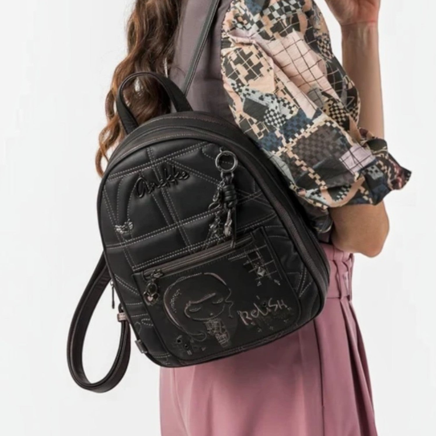 Woman wearing a black Lieblingstasche backpack with quilted stitching and graphic embroidery on her shoulder
