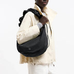 Lieblingstasche Moon Bag Ruffle Large in black, made from recycled fishing nets, worn as a shoulder bag by a model.