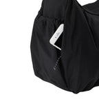 Lieblingstasche black slouchy bag featuring a convenient side pocket with a white smartphone tucked inside