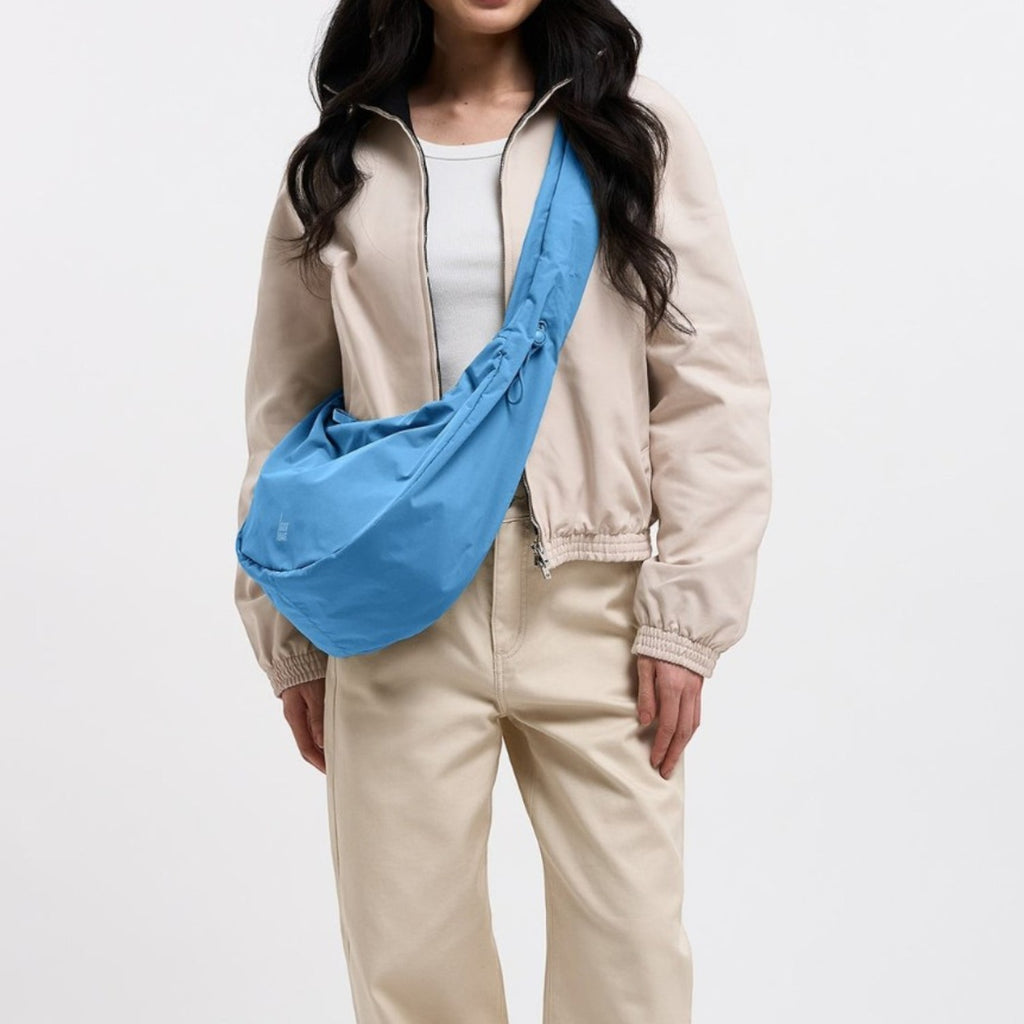 Lieblingstasche large blue moon bag worn by a woman with long dark hair, beige jacket and cream pants.