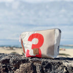 Lieblingstasche Brise pouch made from recycled sailcloth with a red number 3 design, set against a beach background.