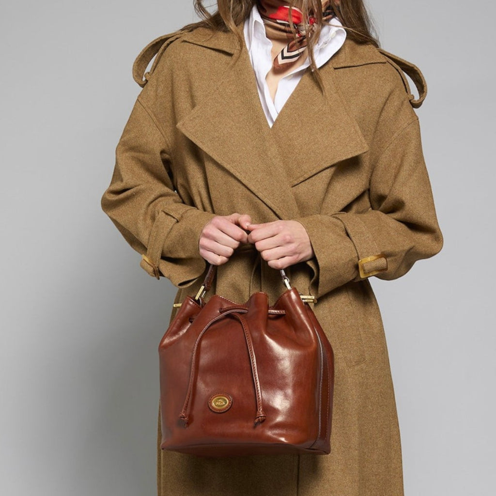 Lieblingstasche brown leather drawstring bucket bag with shoulder strap, worn by a model in a tan coat.