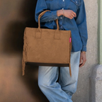 Lieblingstasche Daily Shopper bag in brown suede with fringe details held by a person in denim shirt and jeans