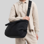 Lieblingstasche Cloud Horizon black padded tote bag worn as a crossbody by a model in a beige textured outfit