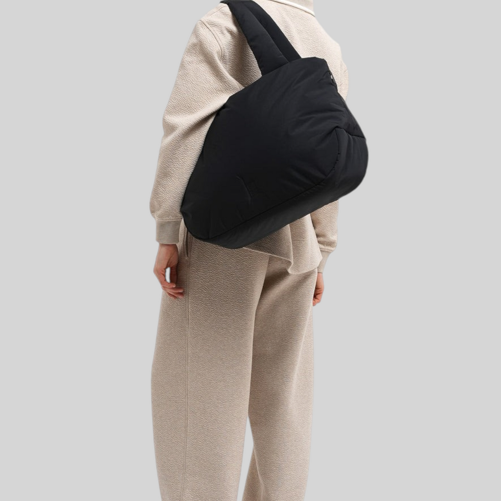Lieblingstasche Cloud Horizon black padded tote bag worn over the shoulder by a woman in a beige lounge set