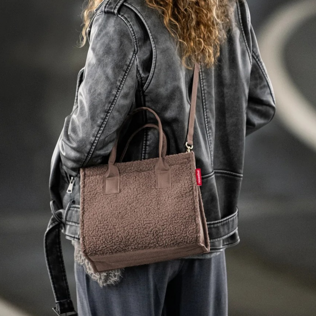 Lieblingstasche Daily Shopper XS in brown teddy fleece worn as a crossbody bag by a woman in a leather jacket