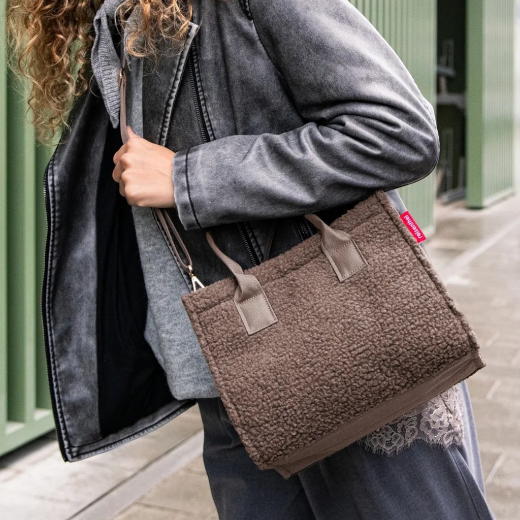 Lieblingstasche Daily Shopper XS in brown teddy fleece material worn over the shoulder by a woman