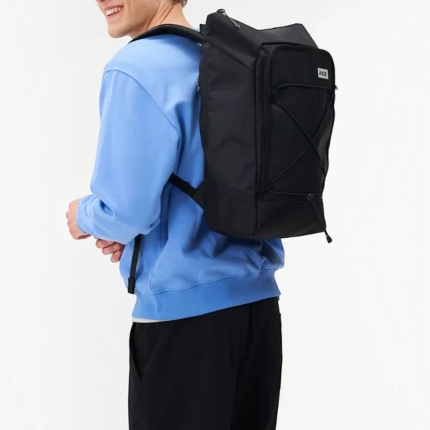 Lieblingstasche Day Pack FLX black backpack worn by a smiling man in a blue sweatshirt against a white background