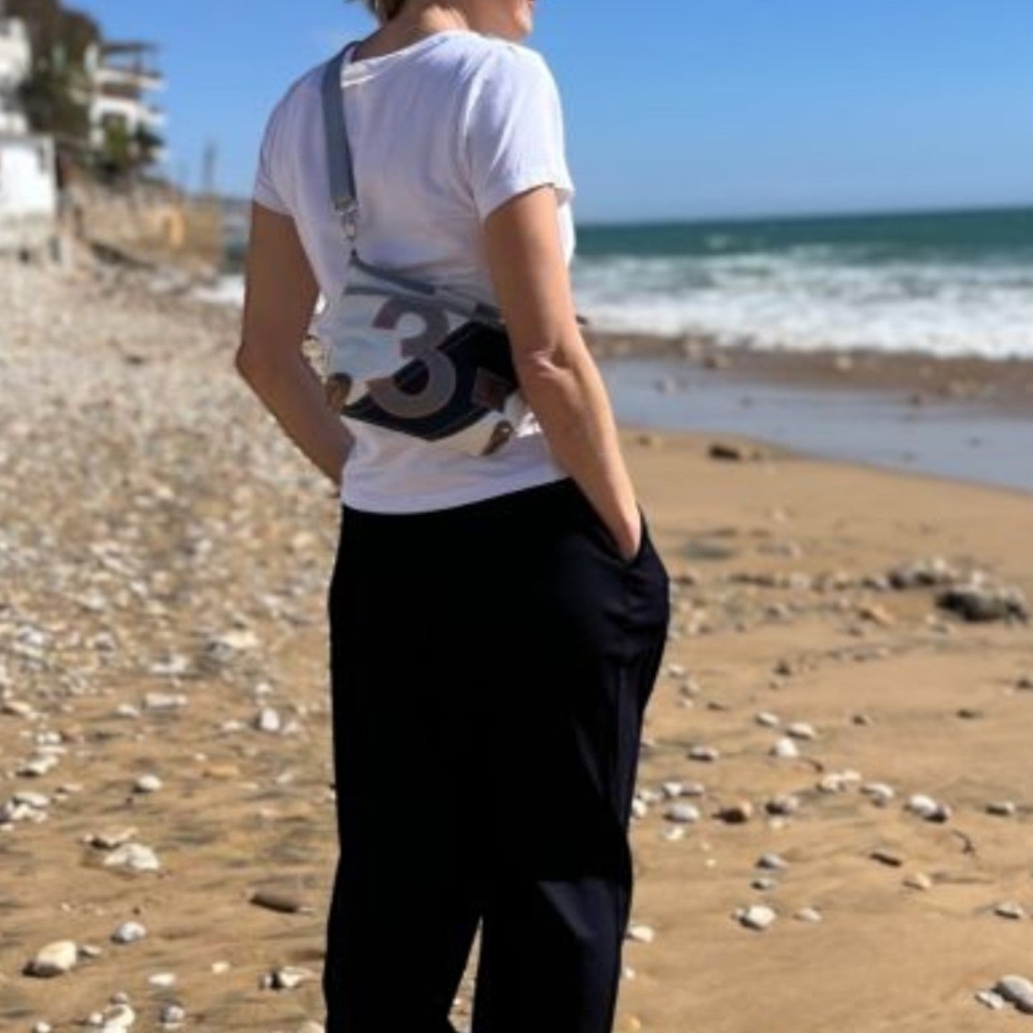 Lieblingstasche Deern Lütt crossbody bag made from recycled sailcloth with number print, worn by woman on the beach