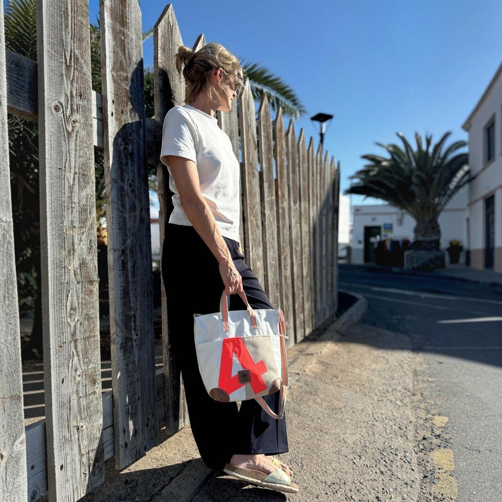 Lieblingstasche Deern Mini canvas tote bag with red letter A detail held by a woman leaning against a wooden fence