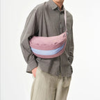 Lieblingstasche sling bag in dusty rose and light blue worn crossbody by a man in a plaid shirt and beige cap