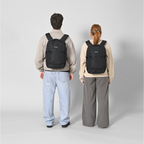 Lieblingstasche eoto Midi20 black 20L city backpack worn by a man and a woman against a light grey background