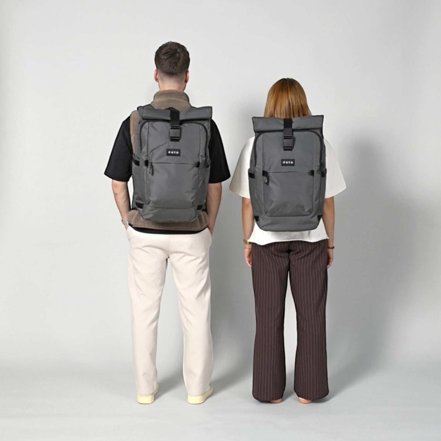 Lieblingstasche eoto Tall41 grey rolltop travel backpacks worn by a man and a woman against a light grey background
