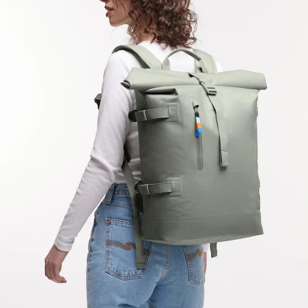 Woman wearing a sage green Lieblingstasche GOT BAG Rolltop 2.0 backpack with adjustable straps and magnetic closure