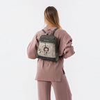 Lieblingstasche grey backpack with Anekke illustration, front zip pocket, and metallic charm on a woman's back