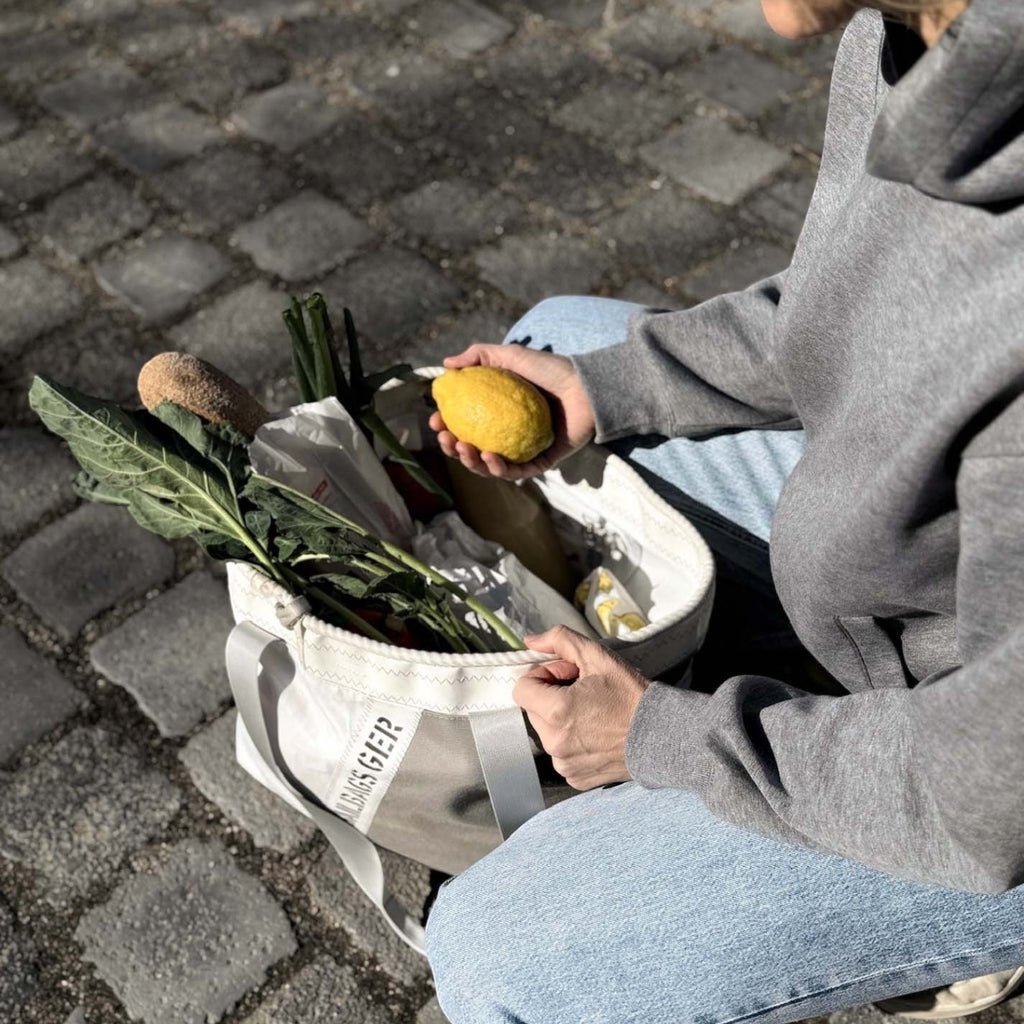 Lieblingstasche grey canvas tote bag filled with groceries, held by a woman in jeans and a hoodie.