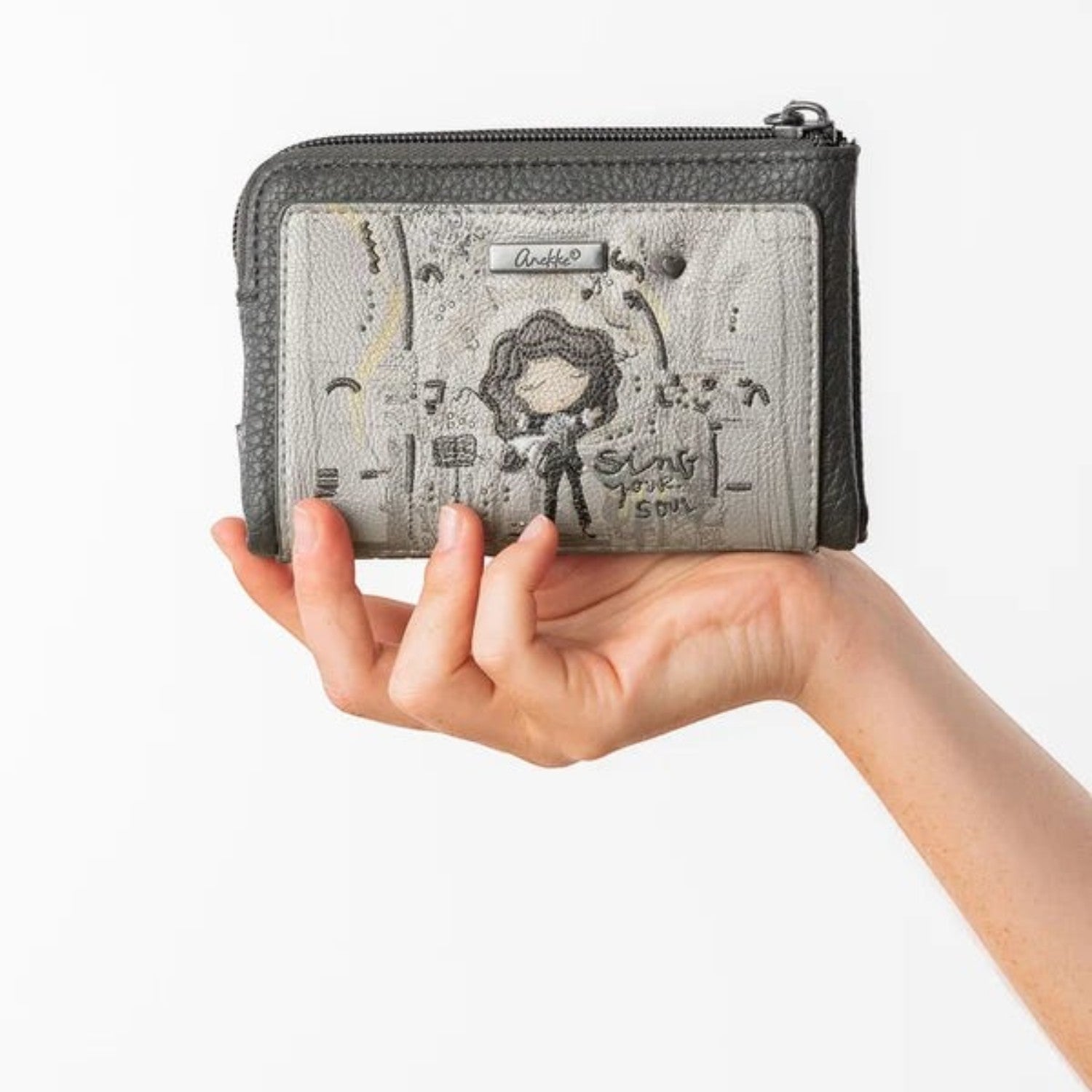 Lieblingstasche grey leather wallet with whimsical girl illustration and Sing Your Soul text held in a hand