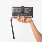 Lieblingstasche grey wallet with musical instrument print, wrist strap, and snap closure held in a hand