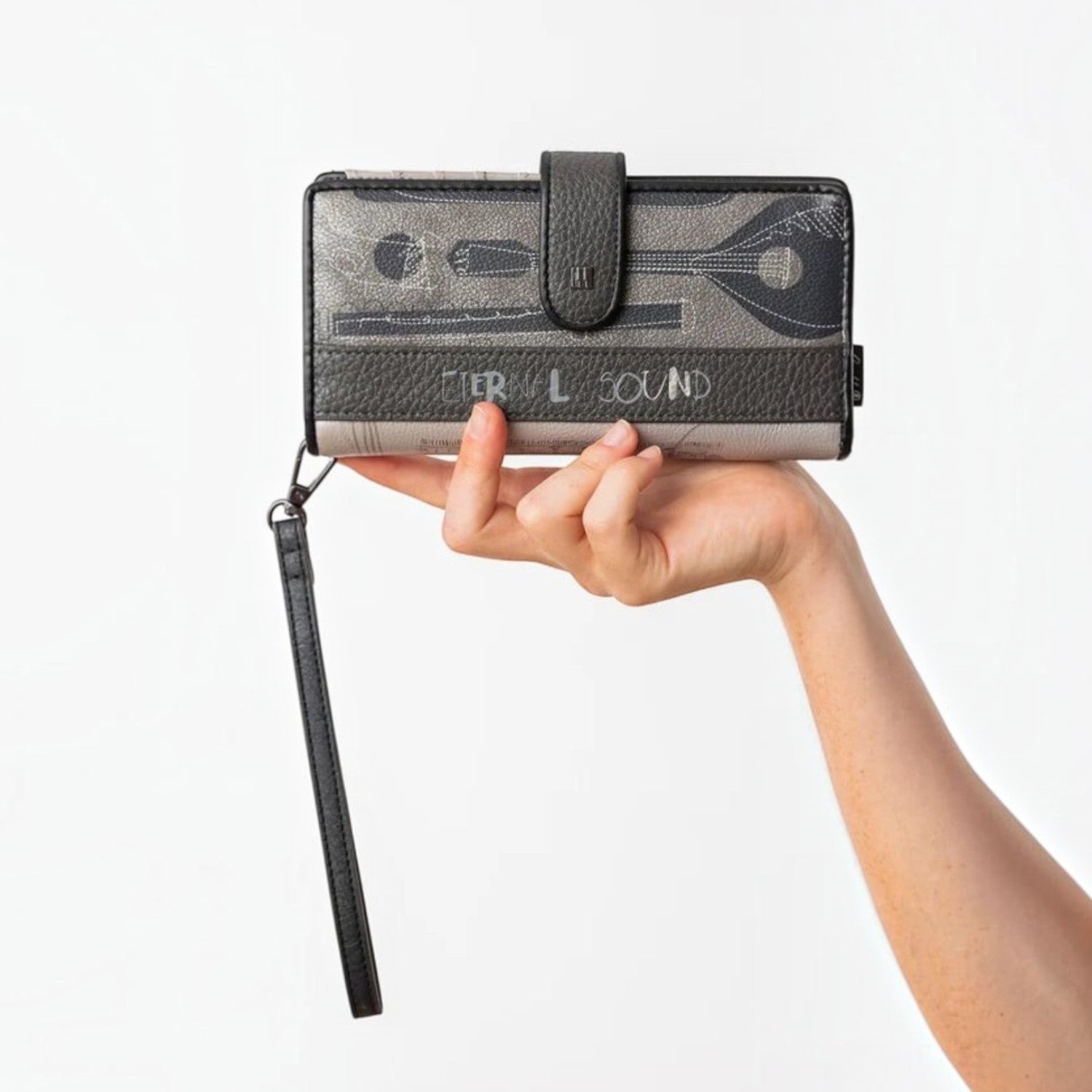 Lieblingstasche grey wallet with musical instrument print, wrist strap, and snap closure held in a hand