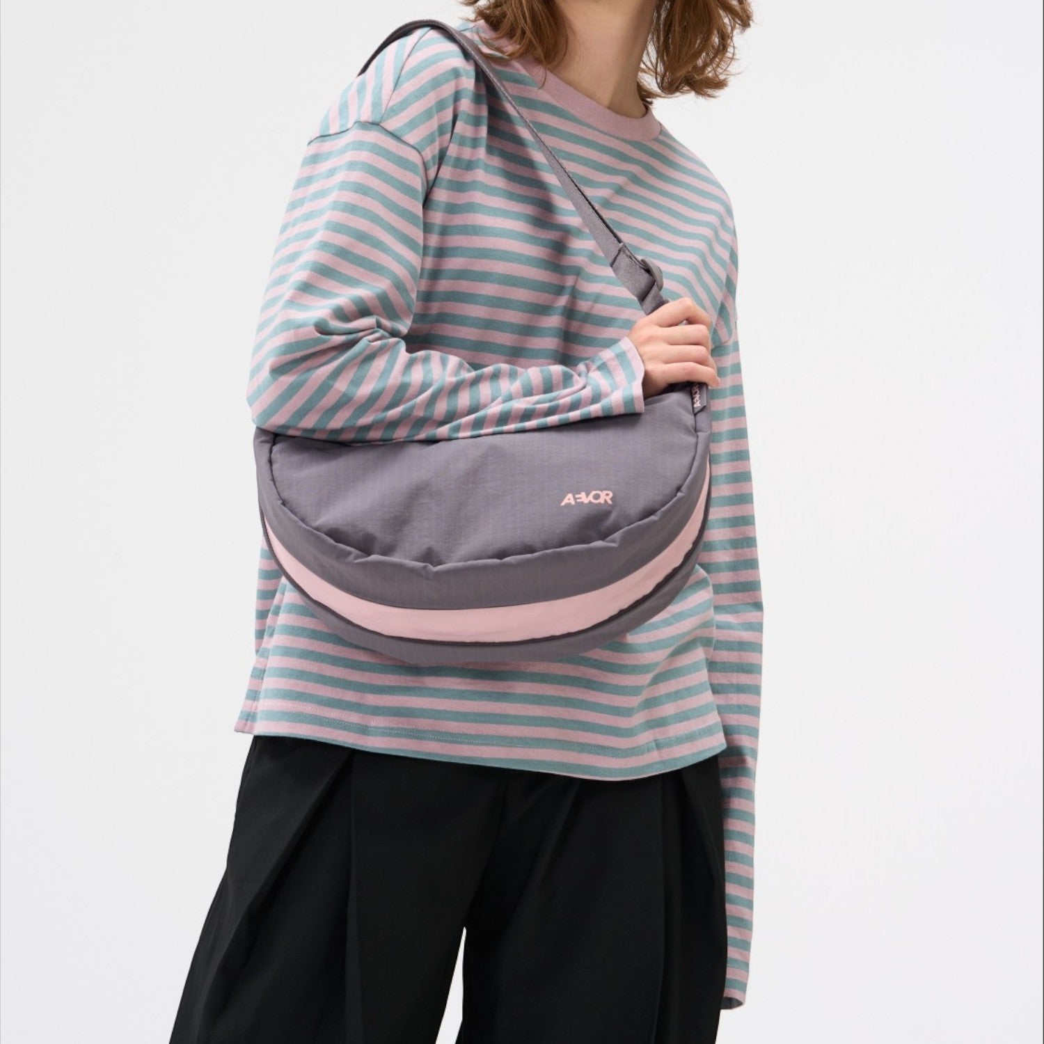 Lieblingstasche sling bag in grey and pink worn by a woman in a matching striped long-sleeve shirt