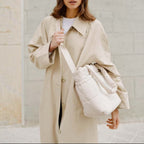 Lieblingstasche Hellvi Cloud Medium bag in cream with padded design worn by a woman in a beige trench coat