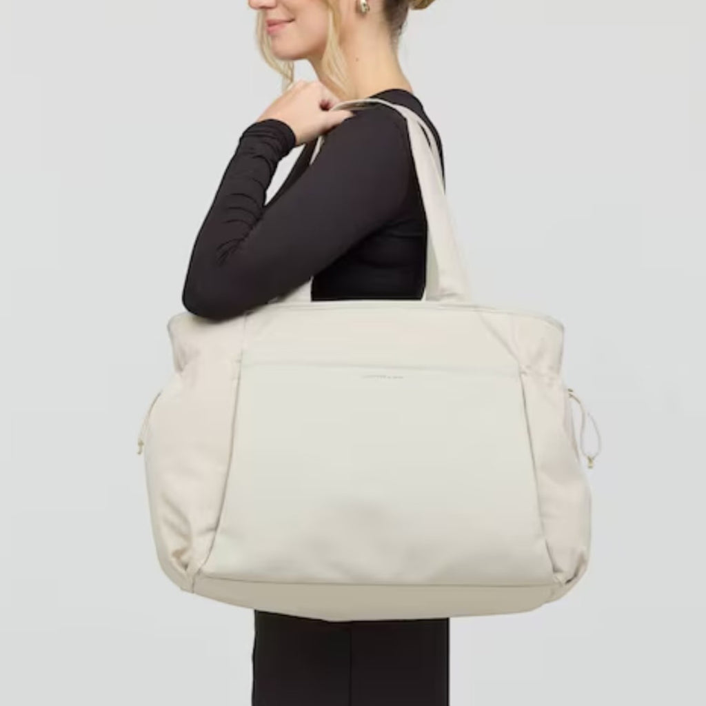 Lieblingstasche Hellvi Pro Large beige tote bag carried on shoulder by a woman in a black long-sleeve top