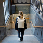 Lieblingstasche Helsinki backpack in off-white worn by a woman walking down subway stairs.