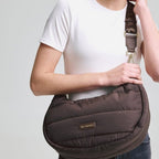 Lieblingstasche Lifetime Buddy M brown quilted crescent shoulder bag with branded strap worn by a smiling woman